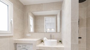 A modern bathroom with a built-in washing machine, a sink, and a mirror.