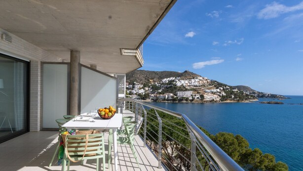 A balcony with a table set for dining, overlooking a coastal town and the sea. - 3-Bedroom Apartment in Roses with Wi-Fi and Parking (Roses)