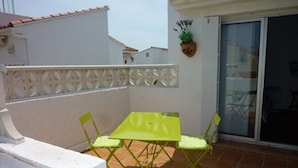A small outdoor patio with a green table and chairs, a white wall, and a potted plant. - Charming 2-Bed Apartment, A/C, Sleeps 4, Near Beach, Parking Included (Port Leucate)