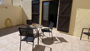 A patio with a table and chairs, a door, and a wall with a textured surface.