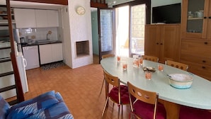 A kitchen with a dining area, a staircase, and a television.