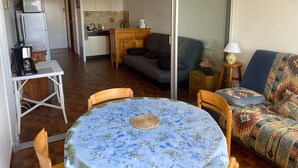 A cozy living area with a dining table, a sofa, and a kitchen in the background. - Studio with Pool, 4 Pers., Port Leucate, Parking (Port Leucate)
