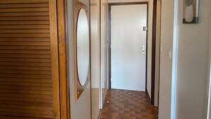 A hallway with a wooden door, a mirror, and a checkered floor. - Studio with Pool, 4 Pers., Port Leucate, Parking (Port Leucate)