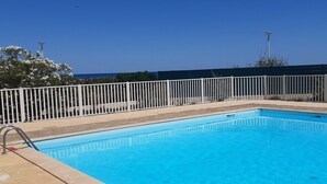 A rectangular swimming pool with a white metal fence, surrounded by a tiled deck. - Studio with Pool, 4 Pers., Port Leucate, Parking (Port Leucate)