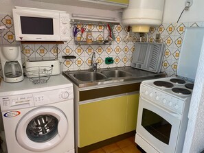 Une cuisine compacte équipée d’un lave-linge, d’un four à micro-ondes, d’un évier et d’une cuisinière.