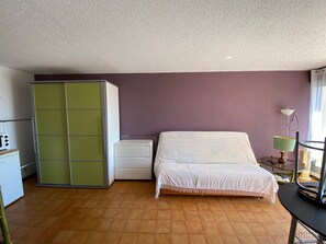 Une chambre à coucher comprenant un lit, une armoire, une table de chevet avec une lampe et une petite table avec une chaise.