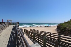 A wooden boardwalk leading to a beach with a clear view of the ocean.