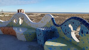 Un banc en mosaïque offrant une vue sur la plage et l’océan.