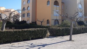A multi-story building with a beige facade, arched windows, and a flat roof. - Charming Garden-Level T2, 4 Guests, Near Beach, Parking Included, Pet-Friendly (Port Leucate)