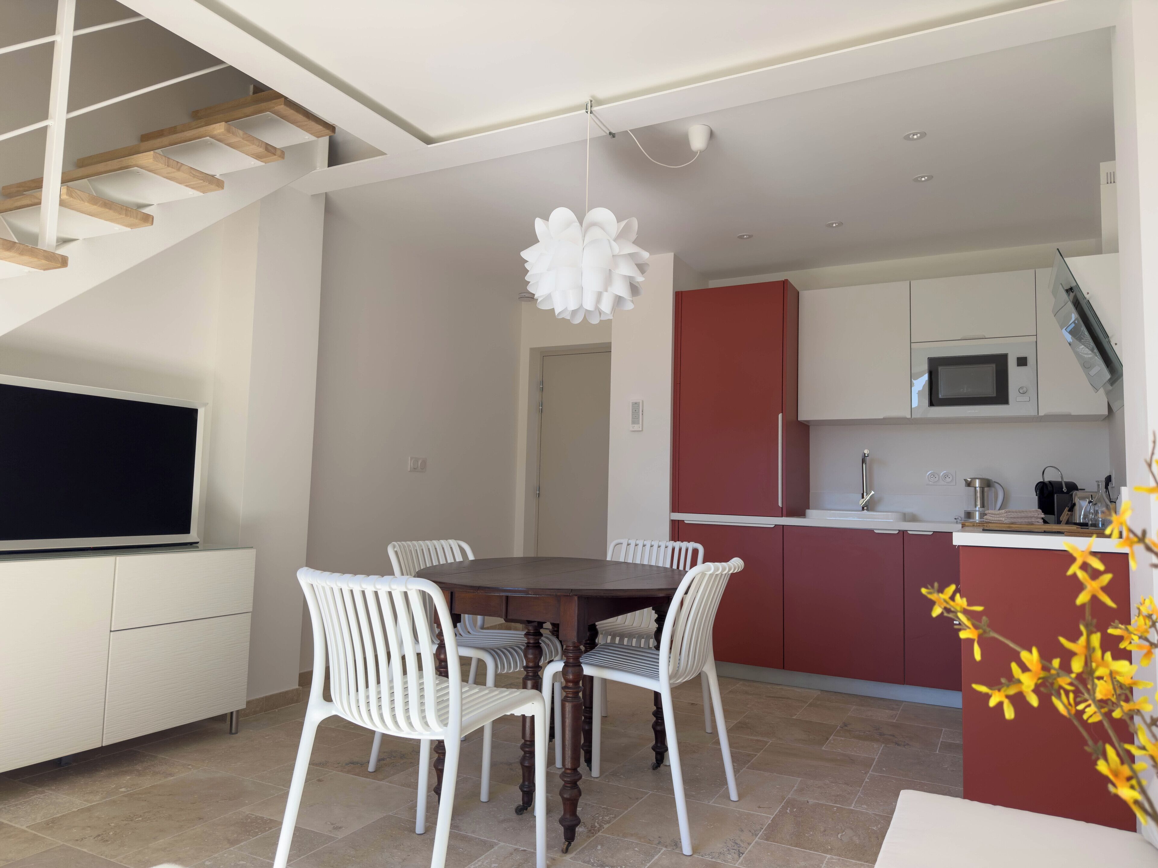 A modern kitchen with white cabinets, a red accent wall, and a built-in microwave.