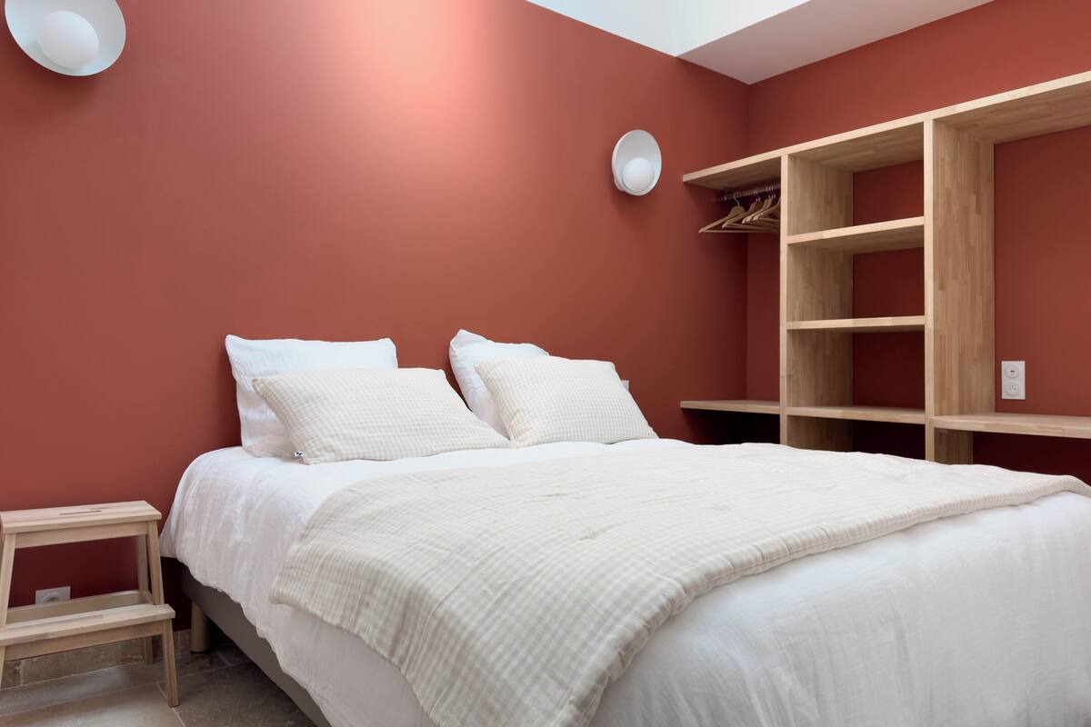 Een slaapkamer met een bed, een houten garderobe en een klein nachtkastje.