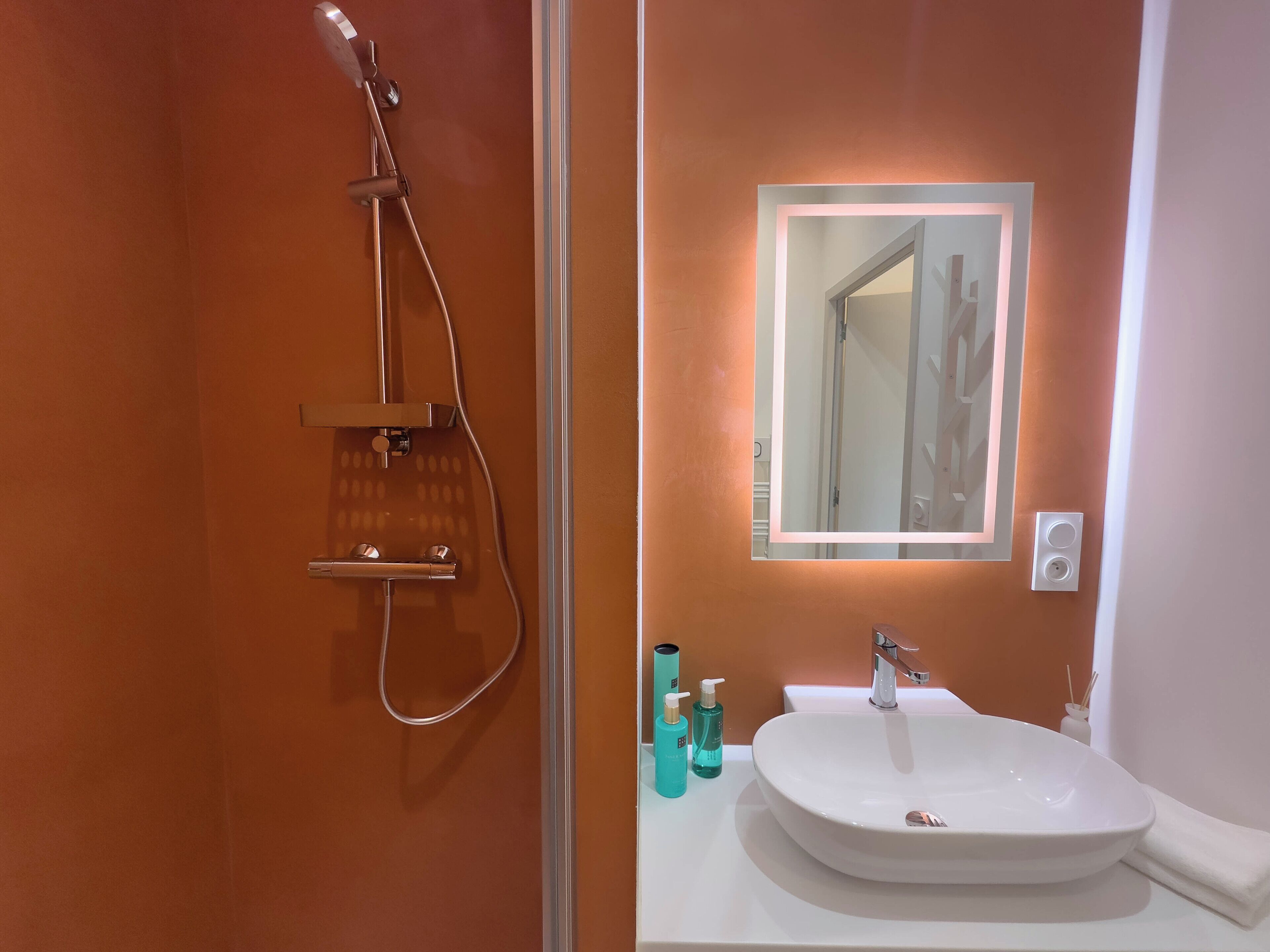 A bathroom with a white sink, a mirror, and a shower.