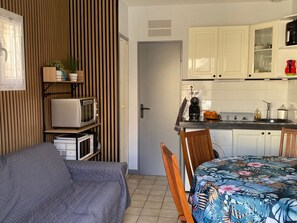 Una habitación pequeña con cama, kitchenette y pared de paneles de madera.