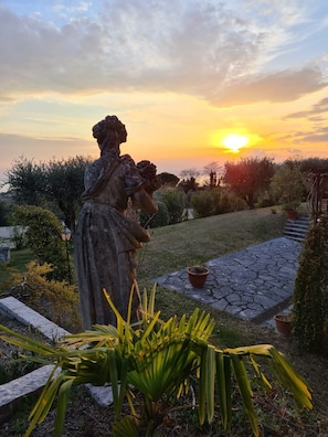 Puutarhassa oleva patsas, taustalla auringonlasku.