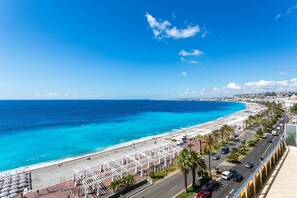 A coastal cityscape with a beach, palm trees, and a road running parallel to the shore. - Royal Luxembourg AP4397 By Riviera Holiday Homes (Niza)