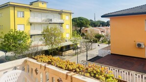 A yellow building with balconies and a small garden area with yellow flowers. - Sunny apartment with balcony-Beahost (Bibione)