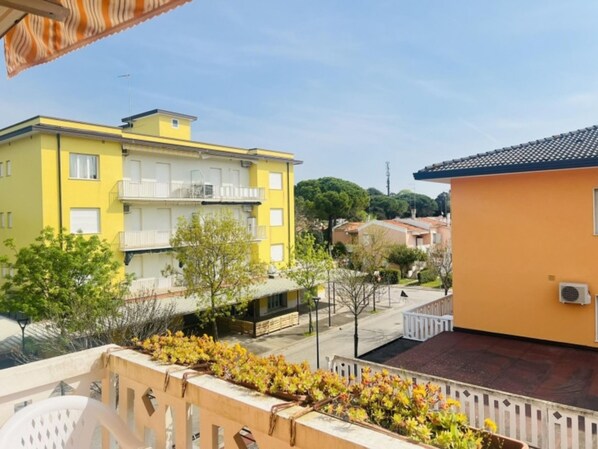 A yellow building with balconies and a small garden area with yellow flowers.