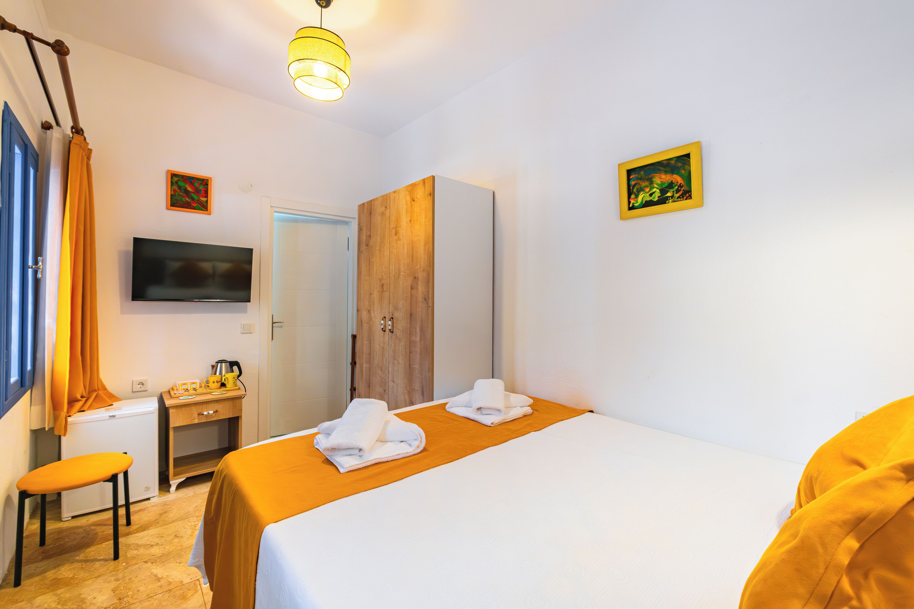 A hotel room with a bed, a desk, a chair, a television, and a wardrobe.