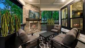 Un patio al aire libre con muros de piedra, una chimenea y asientos.