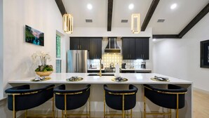 Una cocina moderna con una isla central, taburetes de bar e iluminación colgante.