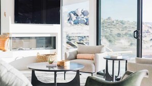 Una sala de estar moderna con chimenea, asientos cómodos y un amplio ventanal con vistas panorámicas.