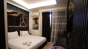Una habitación de hotel moderna con una cama grande, una mesa redonda pequeña y un panel decorativo en la pared.
