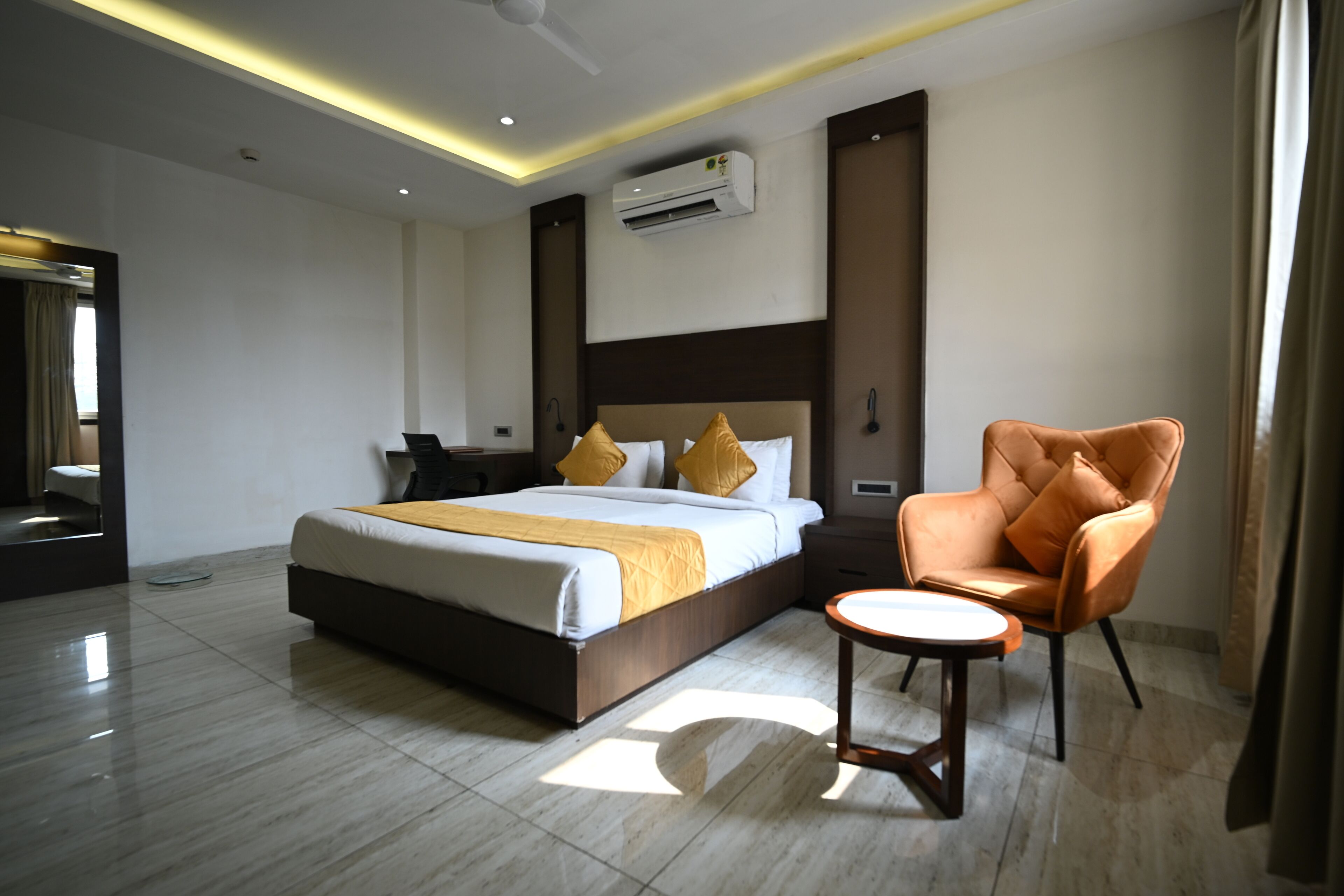 A modern hotel room with a large bed, a seating area, and a flat-screen TV.