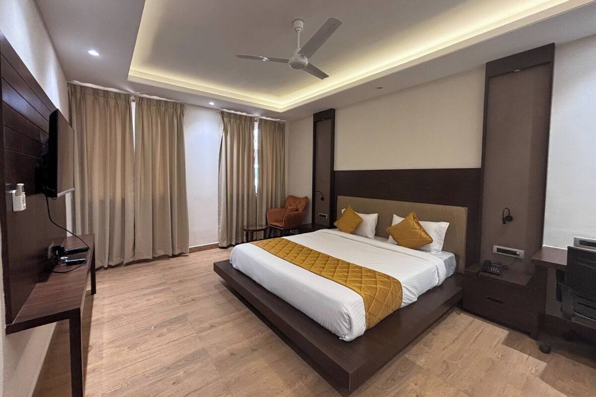 A modern hotel room with a large bed, a ceiling fan, and a flat-screen TV.