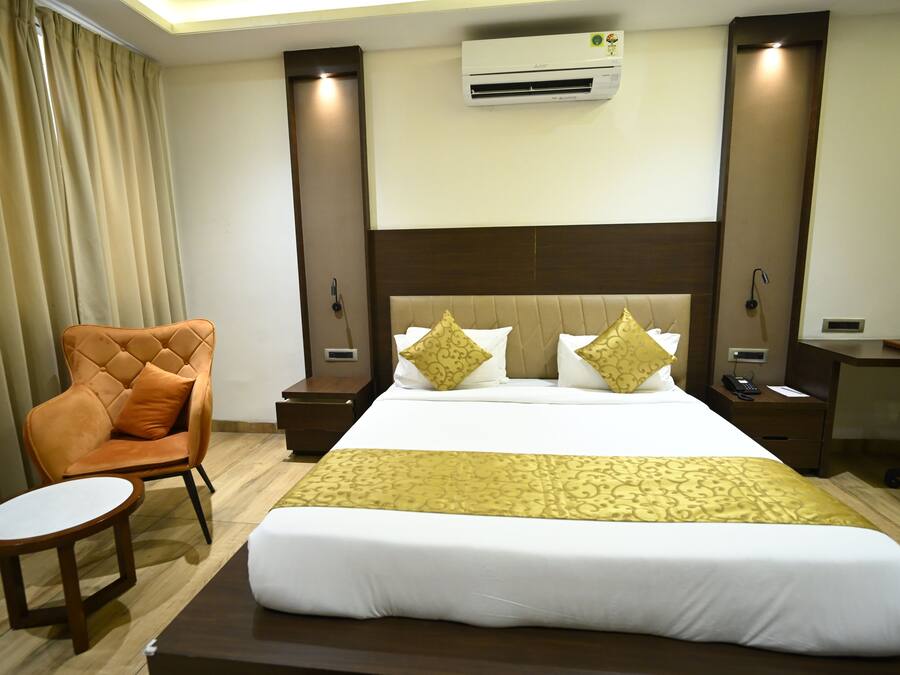 Habitación de hotel con una cama grande, una silla, un escritorio y un equipo de aire acondicionado.