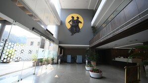 A spacious lobby with a modern design, featuring a large wall mural, potted plants, and a reception desk. - Rohika AAU-IGH (Guwahati)