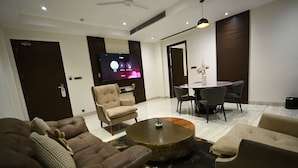 A modern living room with a flat-screen TV, comfortable seating, a dining area, and a ceiling fan. - Rohika AAU-IGH (Guwahati)