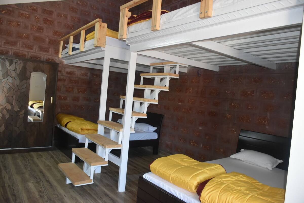 Ein Zimmer mit Etagenbetten, einer Holzleiter, einem Spiegel und einer Wand mit Steinmuster.
