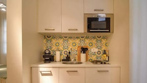 A compact kitchen with a microwave, a sink, and a patterned backsplash. - Le Marais Moderne (Paris)