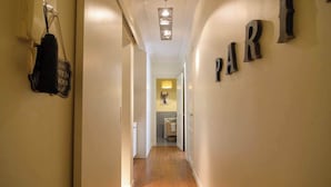 A hallway with a wooden floor leading to a bathroom. The word "PARI" is visible on the wall. - Le Marais Moderne (Paris)