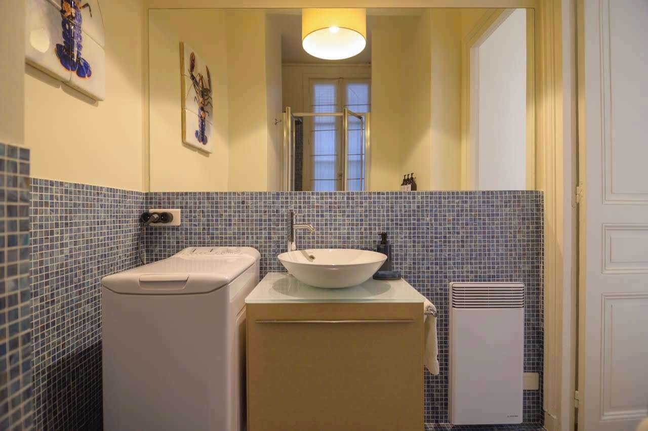 A bathroom with a white sink, a mirror, a towel rack, and a heater.