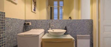 A bathroom with a white sink, a mirror, a towel rack, and a heater.