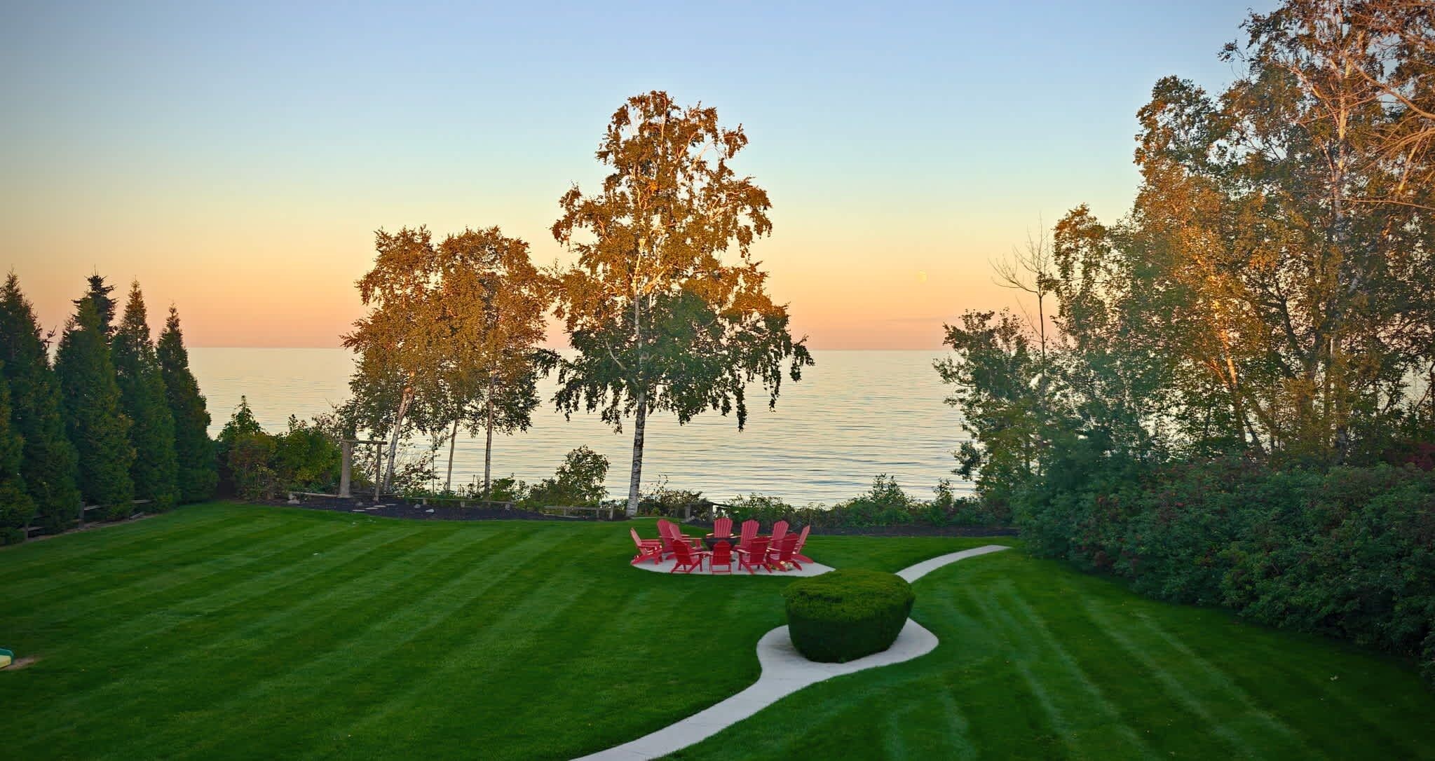 A well-manicured lawn with a seating area and a view of the water.