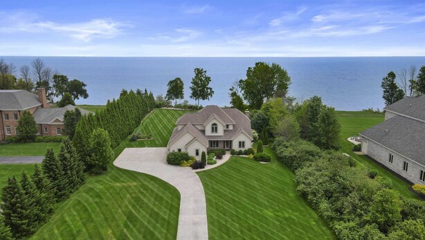 Une grande maison avec une pelouse bien entretenue et une allée menant à l’entrée.