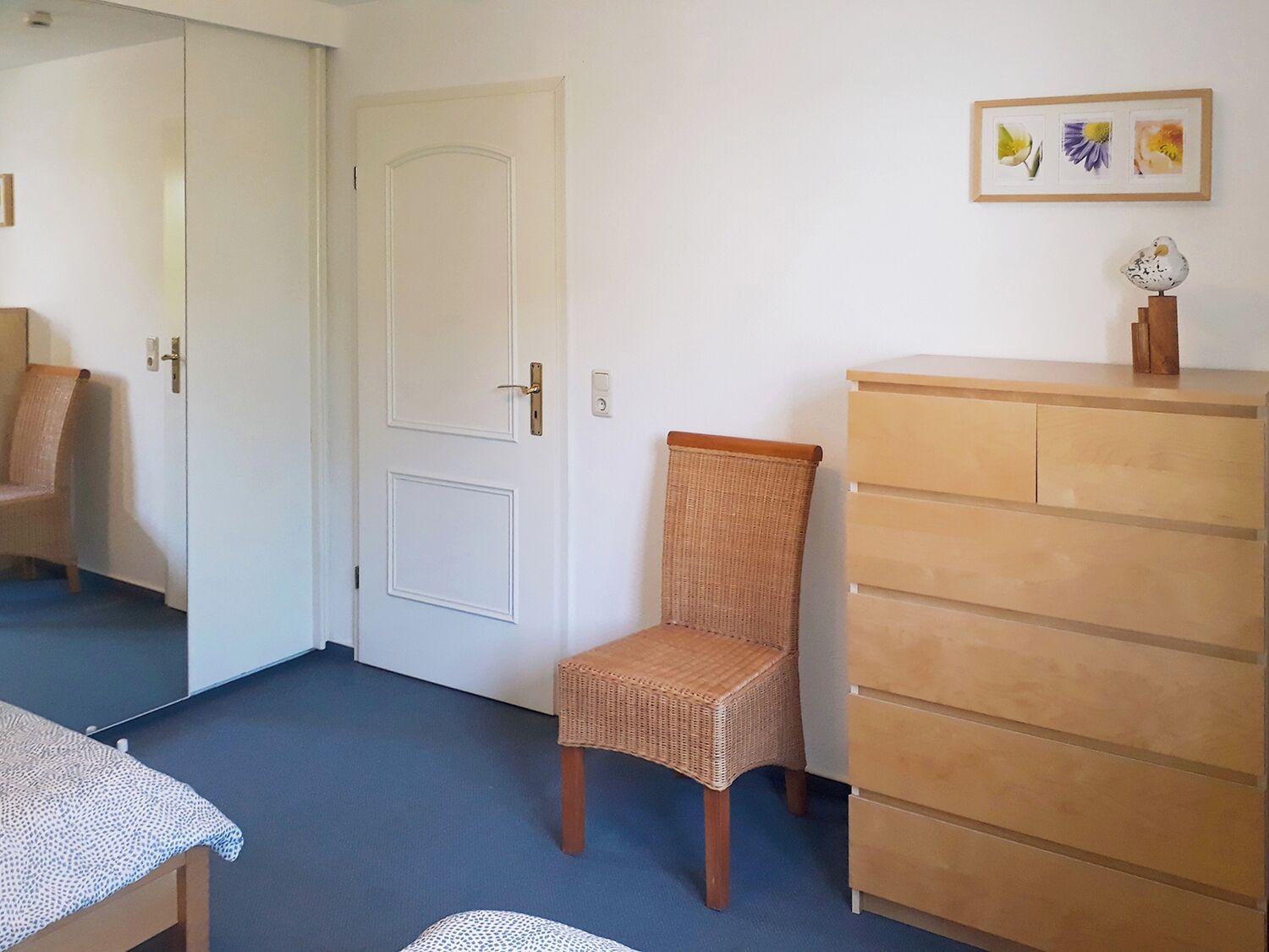 Ein Zimmer mit einem Holzbett, einem Schminktisch und einer Tür.