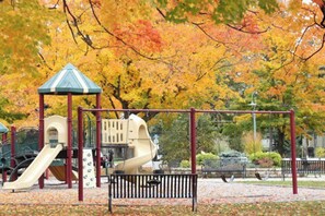 Explore the playground area with a play structure featuring a slide and climbing wall, surrounded by a fence and benches.