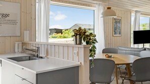 Eine moderne Küche mit Spüle, ein Essbereich mit Tisch und Stühlen sowie Blick ins Freie.