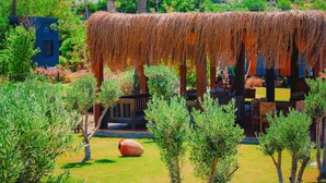 A thatched structure with a view of wind turbines and a hilly landscape. - Flu Alaçatı Tiny House Otel (Çesme)
