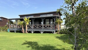 A two-story building with a balcony, surrounded by a well-maintained lawn and palm trees. - Flu Alaçatı Tiny House Otel (Çesme)