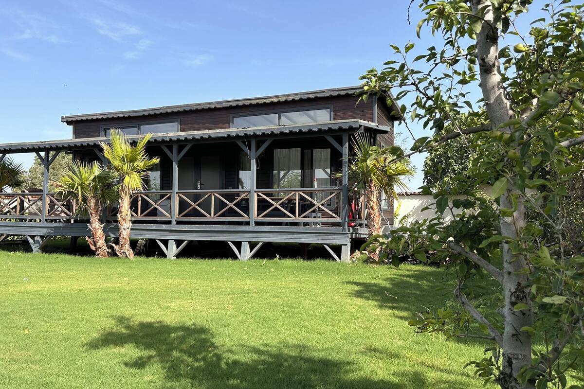 A two-story building with a balcony, surrounded by a well-maintained lawn and palm trees.