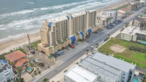 Un hôtel situé sur la côte, avec plusieurs étages, un parking et une vue sur la plage et l’océan.