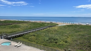 Una playa con un muelle de madera, una piscina y una zona ajardinada.