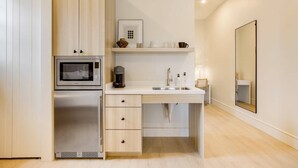 Een moderne keuken met een ingebouwde magnetron, koffiezetapparaat en een spoelbak.