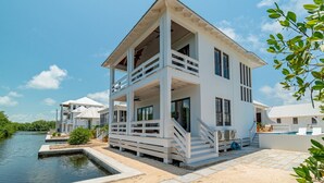 Ein weißes, zweistöckiges Haus mit Balkon, Schwimmbad und Steg, der ins Wasser ragt.