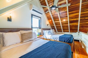 Una habitación con dos camas, techo de madera, aire acondicionado y una ventana.