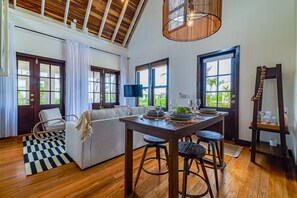 Una habitación amplia con comedor, sofá, televisor y ventanas grandes.